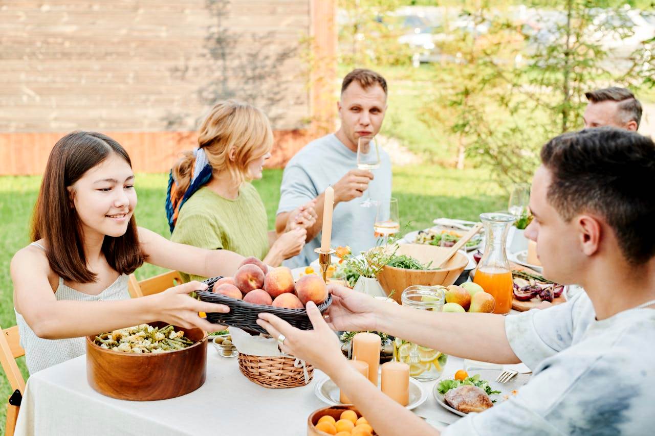 pexels-julia-m-cameron-8841463 Five people dining together at a table full of food outside.